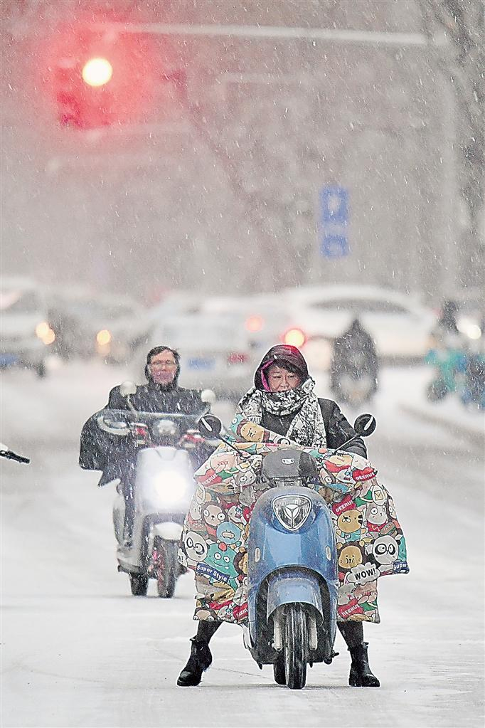 市民驾驶电动车驶过湿滑的路面。记者 马楠 王洋 摄 （图片除署名外均由受访单位提供）