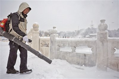 12月14日，北海公园，工作人员拿着吹雪机除雪，确保游客游览安全。新京报记者 薛珺 摄