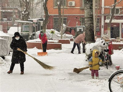 12月14日，丰台区西罗园街道西罗园第四社区，居民们参与扫雪铲冰，一位小朋友也跟在大人身边学着扫雪。