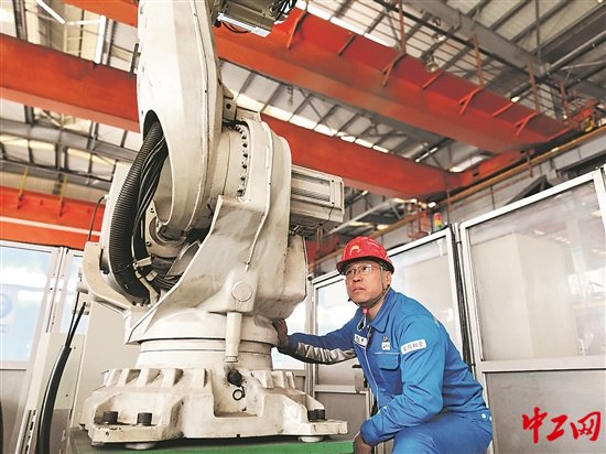 曹文军在观察管端焊缝自动修磨机器人运行情况。工人日报-中工网通讯员 杨宏智 摄