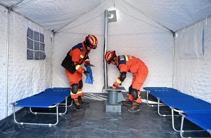 12月19日，在积石山县大河家镇大河村安置点，救援人员在安装火炉。本文图片 新华社 图