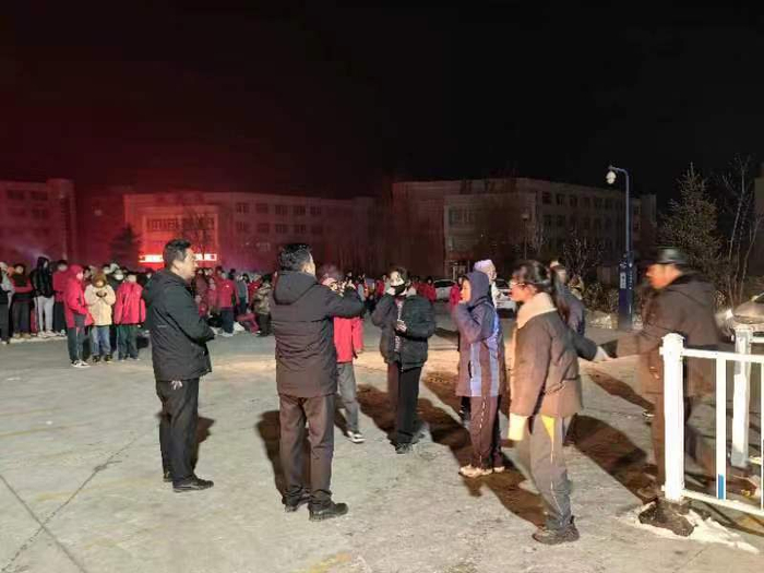 在积石山县移民中学，操场上老师们和学生们一起等待家长到来。（受访者供图）