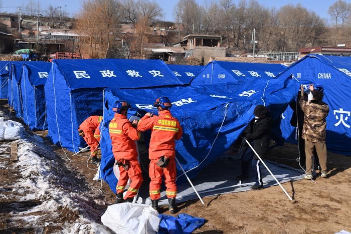 12月20日，在积石山县石塬镇沈家坪村安置点，救灾人员为受灾群众搭建帐篷。新华社记者 范培珅 摄