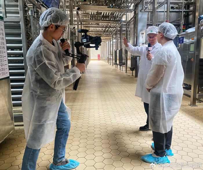 图为蒙牛曲靖工厂负责人马福利向记者介绍如何通过优化车间设计，削减生产能耗。