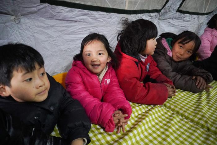 12月22日，甘肃省临夏州积石山县大河家镇康吊村，小朋友在安置点的“帐篷小课堂”参加集体活动。新华社记者 马希平 摄