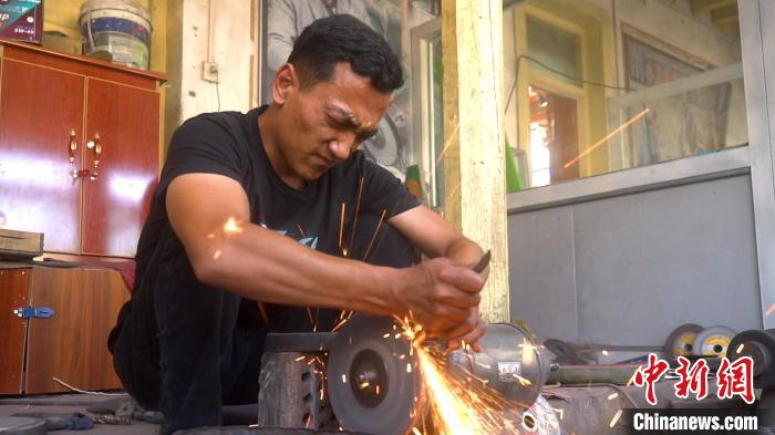  阿卜杜拉·阿卜杜赛麦提在工作间打磨刀具。李明非摄