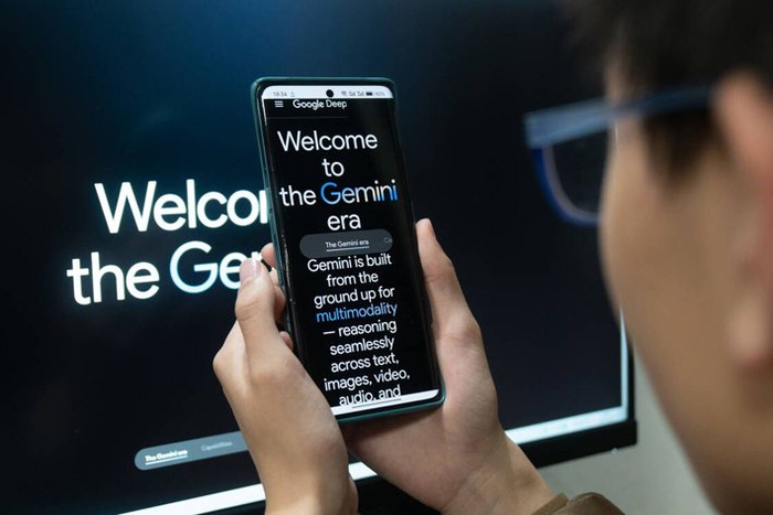 2023年12月11日，上海，一位年轻人通过手机和电脑关注谷歌新发布的人工智能模型Gemini 视觉中国图