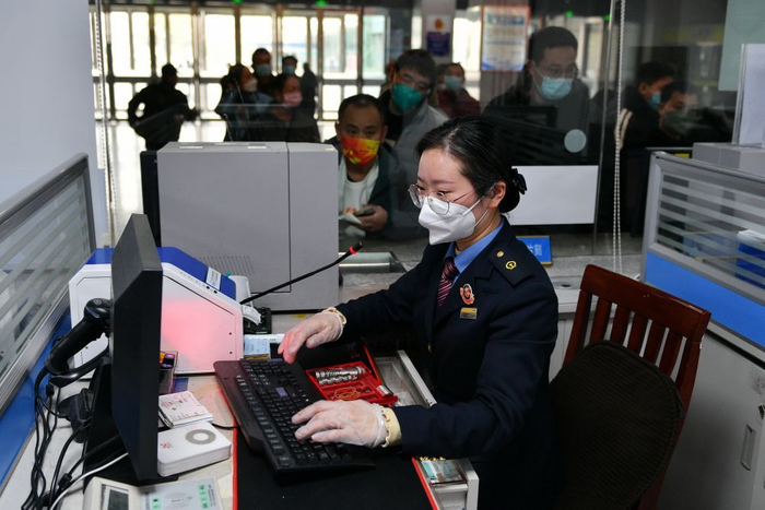 ↑2023年1月1日，江苏常州火车站铁路工作人员在售票处为乘客出售火车票。新华社发（史康 摄）