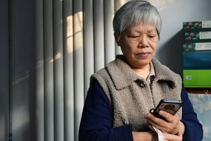 12月19日，高淑英在晖达社区的家中查看手机。新华社记者 吴刚 摄