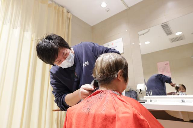 惠老大集“服务区”，一名志愿者为老年居民理发。  新京报记者 王子诚 摄