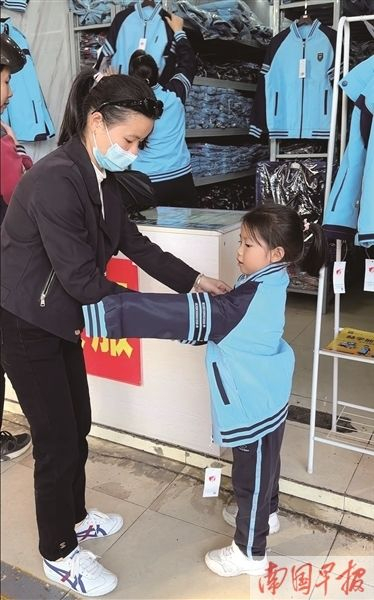 一名学生家长正在给孩子试穿南宁校服。记者 邹财麟 摄