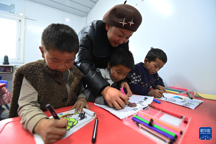 12月27日，在积石山县大河家镇梅坡小学临时教学点，老师指导小学生画画。新华社记者 范培珅 摄