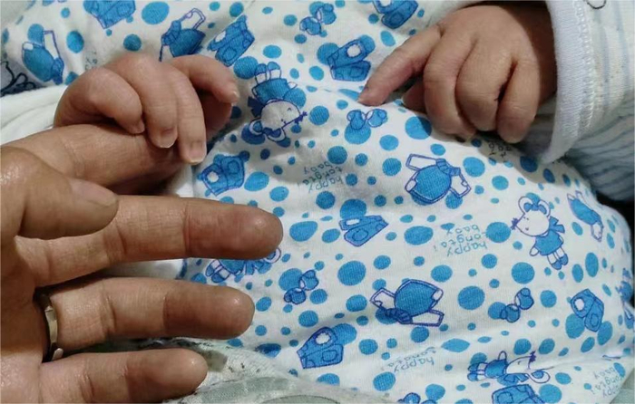 刚刚出生的“地震宝宝”握着妈妈的手（12月20日摄，受访者供图）。