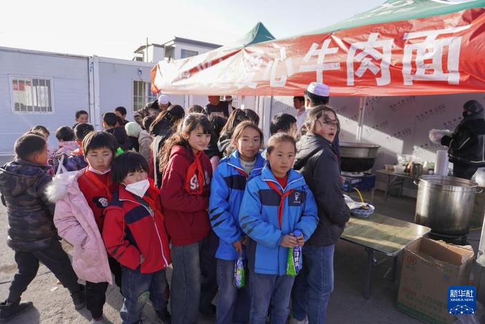 12月29日，在积石山县柳沟乡尕集村板房安置点，学生们放学后等待吃饭。新华社记者 马希平 摄