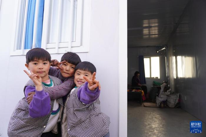 12月29日，在积石山县柳沟乡尕集村板房安置点，小朋友在板房门口玩耍。新华社记者 马希平 摄