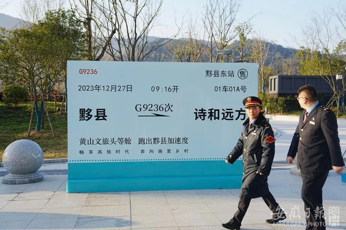两名工作人员从黟县东站特大的车票前经过。（李博 摄）