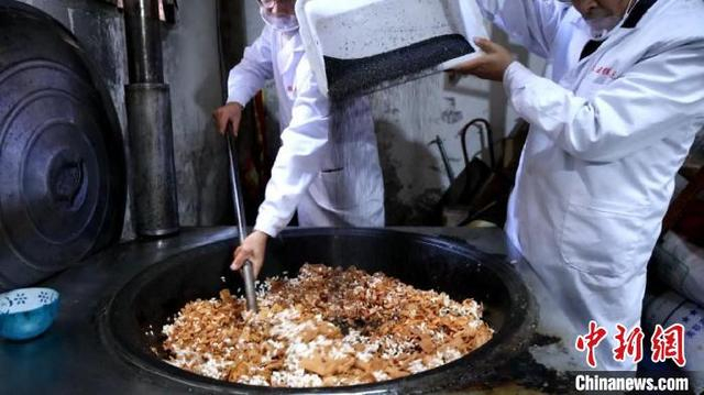 制糖师傅将黑芝麻导入锅中进行搅拌。刘鸿鹤 摄