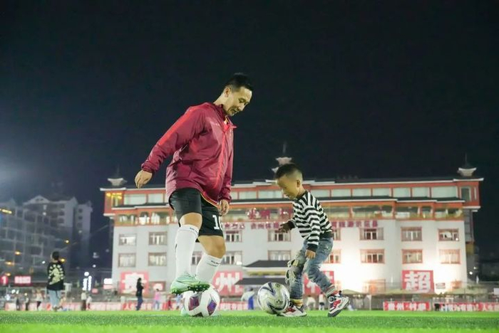 11月7日，“村超”球员、餐饮从业者董永恒在贵州“村超”球场教小朋友踢球。来源：黔东南微报