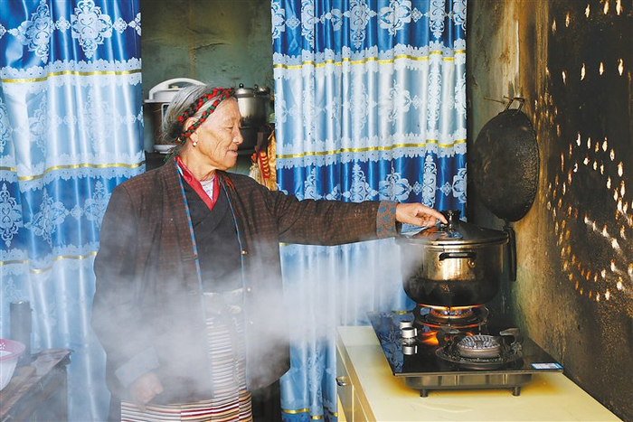 巴果老人使用新式高压锅时，单手拨动锅盖上的泄压阀排放蒸汽。　记者　武沛涛　摄