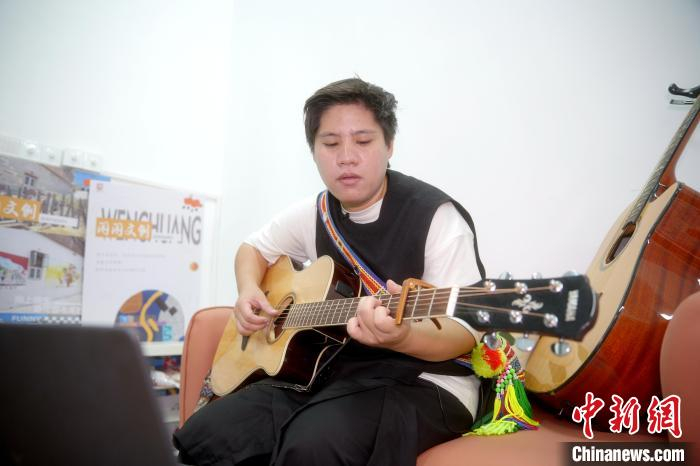 图为赖淑珍边弹吉他边哼唱着歌曲《青青之约》。　中新社记者 李思源 摄