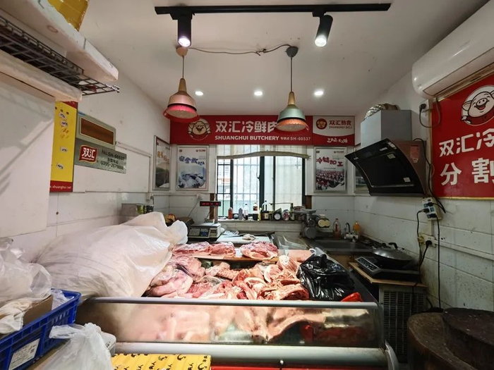 △北艾路双汇冷鲜肉店里，商家将旧的生鲜灯关闭，使用白色射灯照着猪肉。