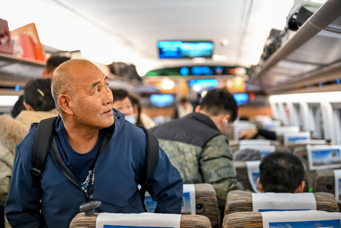 2023年12月30日,在从郑州开往宜兴的g3109次列车上,李世英寻找座位.
