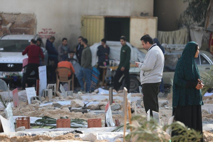 2023年12月31日，人们在位于加沙城希法医院后院的集体墓地悼念逝者。图片来源：新华社