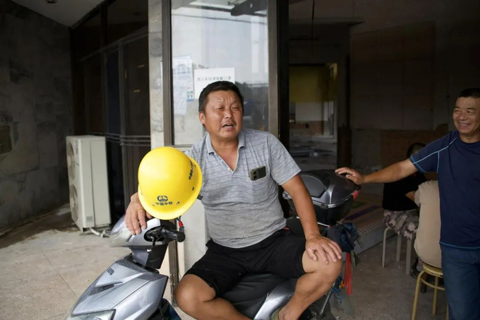 翁兴福（左一）在苏州市吴江区平望镇老汽车客运站门口等待活计。（2023年7月20日）   新华社每日电讯 赵久龙 摄