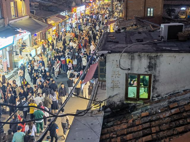 2023年12月31日晚上，亚飞的茶室对面，一扇窗户前的簪花姑娘。新京报记者 周怀宗 摄 