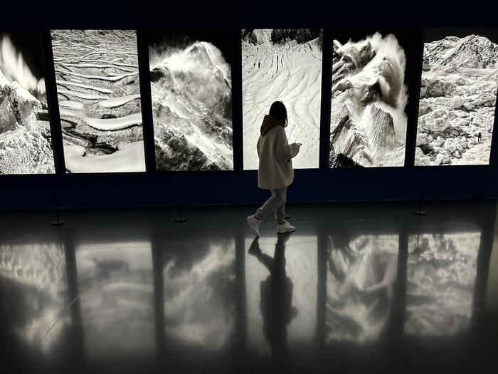 成都市美术馆，一名观众走过“无界·无限”摄影展上的《冰川》组照