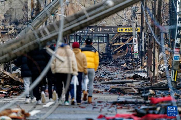  在日本石川县轮岛市，市民们查看“轮岛早市”被地震引发的大火烧毁的废墟 图：新华社