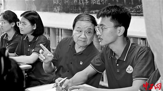 张东海（中）在万宁中学高二年级十二班的数学课上一边听课一边与学生交流。工人日报-中工网记者 赖书闻 摄