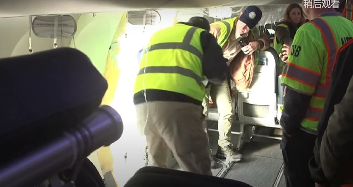 调查人员查看舱门位置的破损