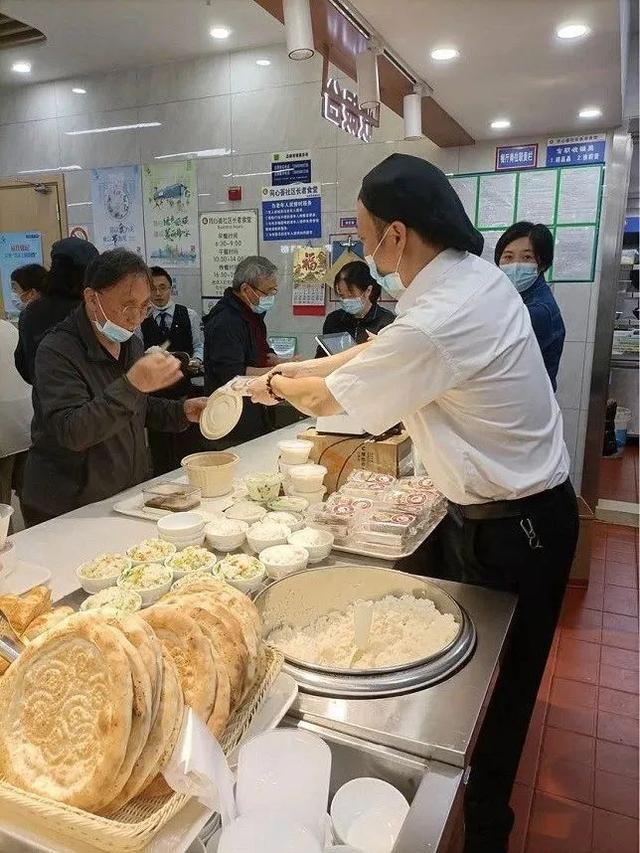 上图：静安寺街道同心荟社区食堂店长杨林在给老人分发重阳糕。