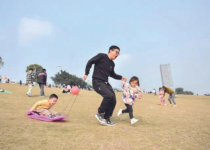     最近重庆天气晴好，南岸区通江大道永宁路口公交站旁，家长带着孩子在草坪上玩耍。据重庆日报