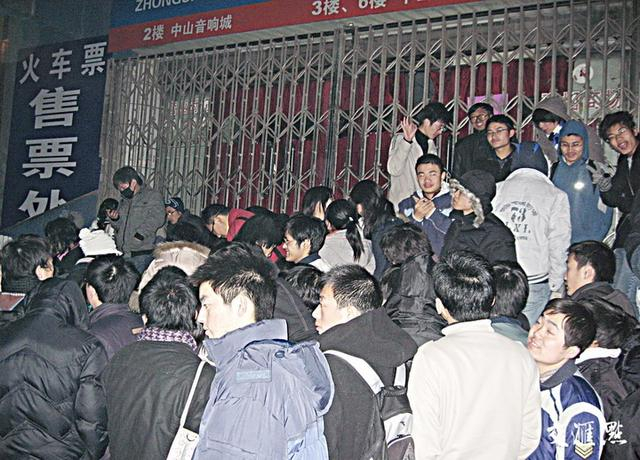 2009年1月8日，南京，寒风中，学生们挤在一起相互取暖，在火车票代售点等候窗口开始售票。 任国勇 摄 视觉江苏网供图