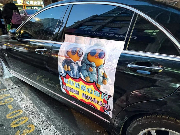 哈尔滨街头停放的私家车上，贴着免费接送南方“小 土豆”的海报。摄影/李莹