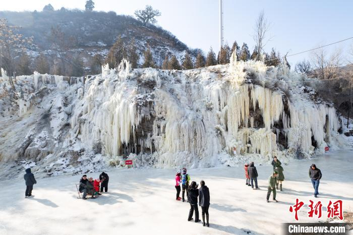 1月10日，山西省太原市店头村，市民在冰面上坐冰车滑冰，在冰瀑前拍照留念。　中新社记者 韦亮 摄