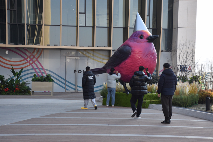 消费者与空中花园的粉红鸟雕塑合影打卡。