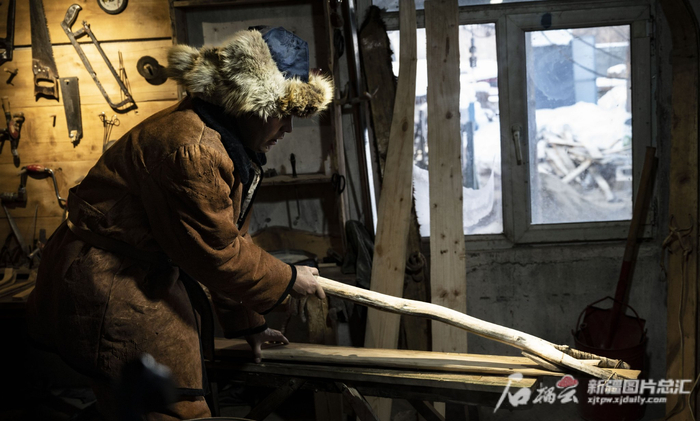 斯兰别克的儿子胡安什别克正在用工具为滑雪板的板头定型。天山网-新疆日报记者 聂宁 摄