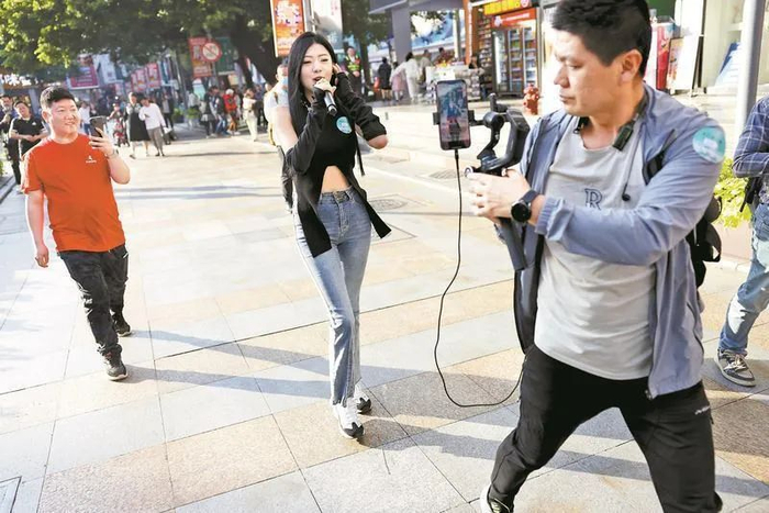 ▲拥有122.7万粉丝的网红主播“爆爆”在东门老街进行才艺表演直播。