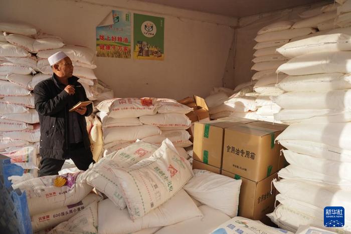   1月17日，在甘肃省临夏州积石山县，一名粮油店的经营者在清点物资。新华社记者 马希平 摄