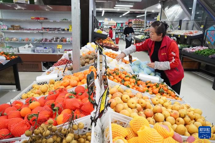   1月17日，在甘肃省临夏州积石山县，一名超市售货员整理水果。新华社记者 马希平 摄