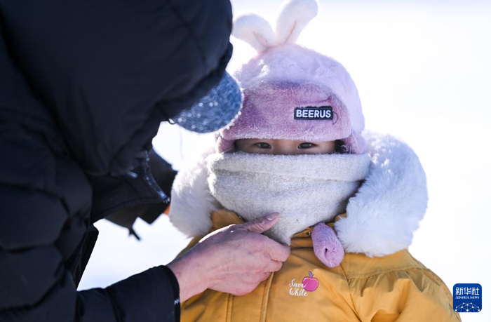　　 1月19日，在内蒙古呼伦贝尔市海拉尔河西新区一处公园，一位家长给孩子戴围巾。新华社记者 连振 摄