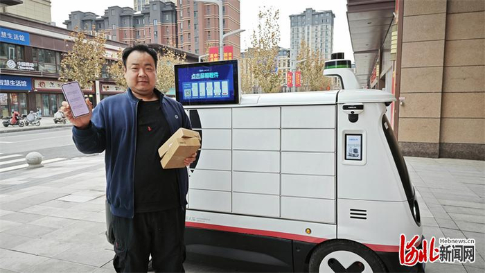 在雄安新区尚德花园小区附近工作的田豹扫码取出快递。河北日报记者曹铮摄