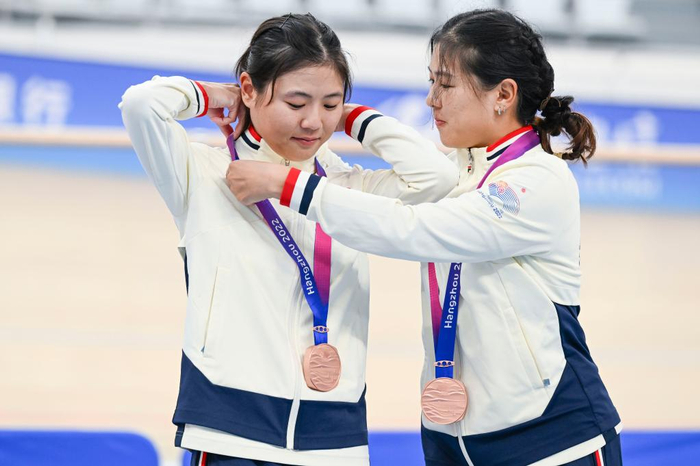 ↑2023年9月27日，中国香港队选手梁宝仪（右）在颁奖仪式上帮助妹妹梁颖仪整理奖牌绶带。