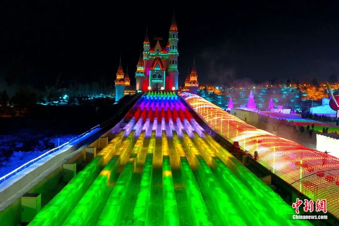 超长冰滑梯夜间五光十色，吸引游客排队体验。张瑶/摄