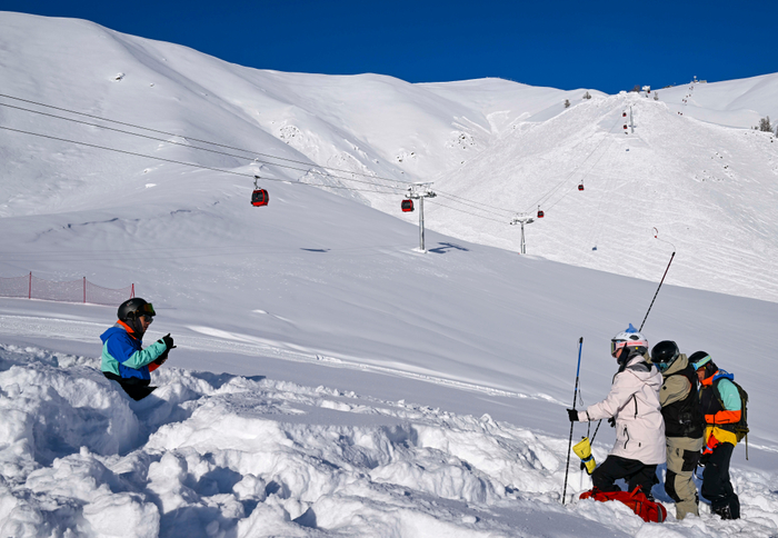 ↑2023年1月13日，旅居新疆阿勒泰的滑雪爱好者彭超（左）在禾木吉克普林滑雪场带领雪友们进行雪崩搜救演习。