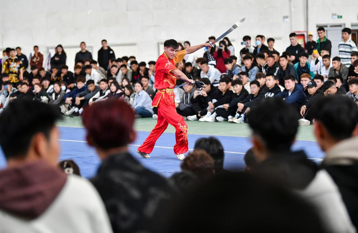 ↑2023年4月20日，阿布都热合曼·巴吐尔江（中）在新疆昌吉学院武术比赛表演选拔赛上展示双刀。