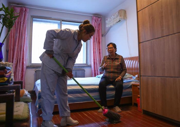 遼寧省瀋陽市和平區文安路社區居家養護中心護理人員幫助社區居民打掃房間。新華社記者龍雷攝